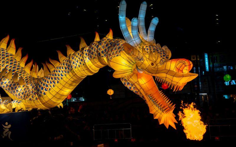Lampion naga besar yang menyemburkan api di tengah parade Festival Lentera Teratai. 
