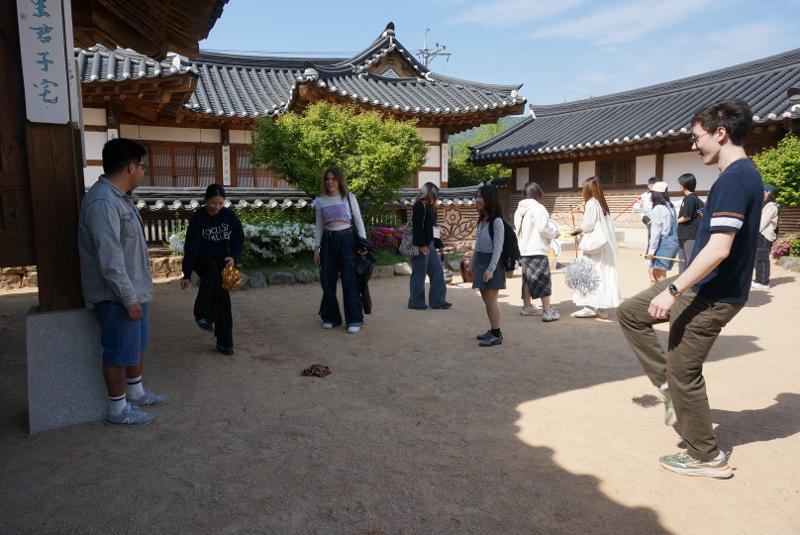 Para pemelajar asing menikmati permainan tradisional Korea, seperti jegichagi dan tuho.