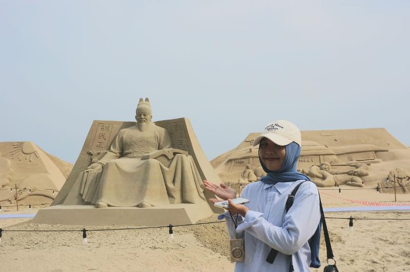 Ardhya berfoto di depan patung pasir Maharaja Sejong. 