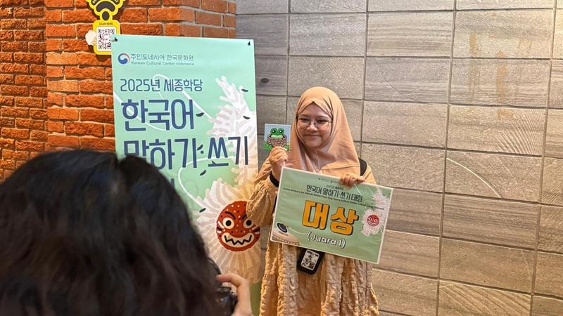 Potret penulis setelah diumumkan sebagai juara pertama dalam Kompetisi Berbicara Bahasa Korea KSI KCCI 2025 dengan membawa lukisan kecil buatan penulis yang menggambarkan ekspresi peribahasa Korea Katak dalam sumur.