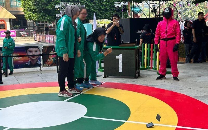 Tiga peserta menjalani permainan pertama dalam sesi Triathlon, yaitu biseokchigi. Salah satu anggota tim harus menjatuhkan batu sasaran. 