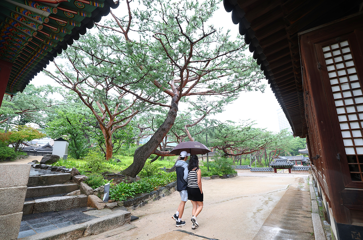 Dua orang wisatawan terlihat sedang berjalan sambil memegang payung di tengah hujan musim panas yang turun di Istana Deoksugung, Jung-gu, Seoul pada tanggal 16 Juli 2025. (Lee Jeong Woo)