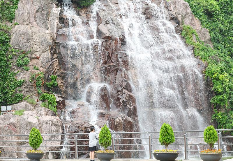 Pada tanggal 7 Juli 2025 seorang warga terlihat sedang menyejukkan diri sambil memandang air terjun di Taman Air Terjun Yongma, Jungnang-gu, Seoul. Hari yang dikenal sebagai Soseo dalam kalender tradisional Korea itu menandai awal puncak dari musim panas. (Lee Jeong Woo)