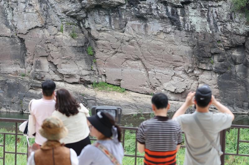 Para warga terlihat sedang mengamati Petrograf Bangudae di Daegok-ri, Ulju pada tanggal 13 Juli 2025. Pada tanggal 12 Juli 2025 Petrograf di sepanjang kali Bangucheon resmi masuk dalam daftar Warisan Dunia UNESCO. (Yonhap News)