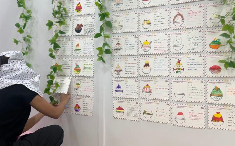 Kartu pos hasil karya peserta yang dihiasi gambar bingsu dan ucapan ulang tahun untuk KCCI dipajang di sudut Multifunction Hall KCCI. 