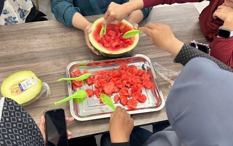 Para peserta saling bahu-membahu menyendok buah semangka dan melon sebagai tahapan awal pembuatan minuman musim panas khas Korea bernama subak hwachae. 