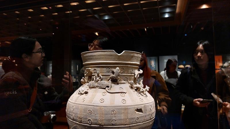 Sebuah karya tembikar berupa pot memiliki desain yang unik dengan figur-figur kecil yang disebut Tou menghias sepanjang leher pot. 