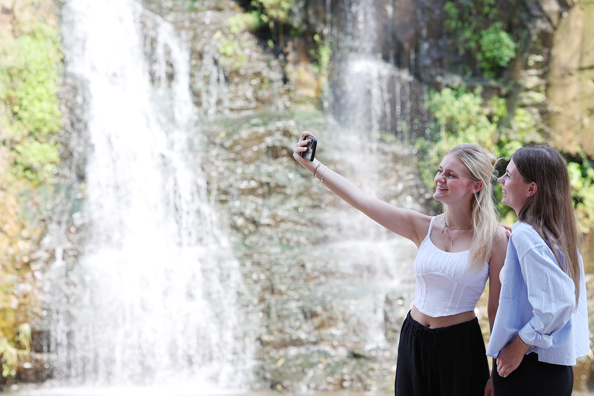 Dua orang wisatawan asing terlihat sedang berfoto pada tanggal 21 Agustus 2025 di depan Air Terjun Hongjecheon yang terletak di Seodaemun-gu, Kota Seoul. Peringatan gelombang panas dikeluarkan hampir di seluruh wilayah Korea pada hari itu. (Lee Jeong Woo)
