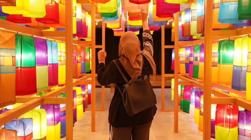 Penulis berfoto di instalasi terowongan dengan lentera warna-warni. 