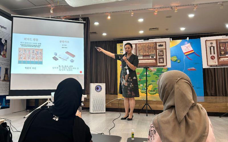 Kim Hyun-joo, Manajer Umum KCCI, sedang menjelaskan fungsi, sejarah, dan simbolisme benda-benda yang ada di sarangbang dan anbang kepada peserta acara. 
