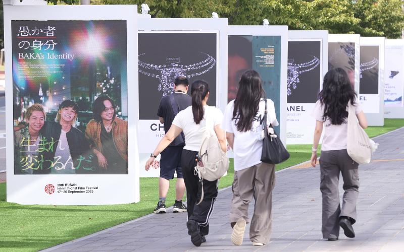 Pada tanggal 17 September 2025 para warga terlihat sedang melintas di samping materi promosi Festival Film Internasional Busan di sekitar Busan Cinema Center, Haeundae-gu, Busan. (Yonhap News)
