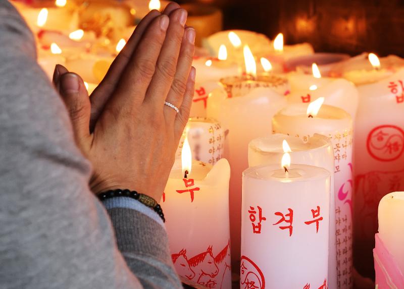Seorang orang tua terlihat sedang menyalakan lilin dan berdoa untuk keberhasilan akademik anaknya di Kuil Yongjusa, Kota Hwaseong, Provinsi Gyeonggi, pada 13 Oktober, sebulan sebelum ujian masuk perguruan tinggi. (Yonhap News)