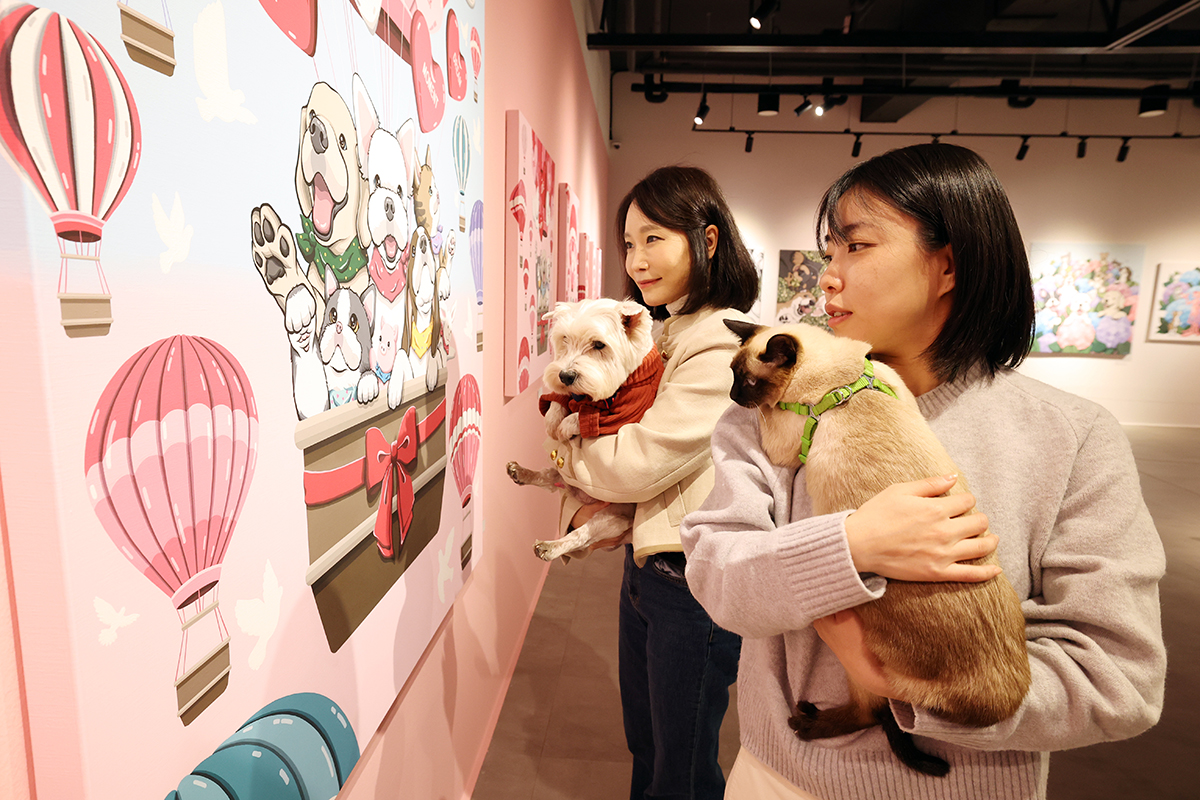 Seniman Cho Wonkyung (kiri) bersama anjingnya dan seniman Jo Min-seo bersama kucingnya pada tanggal 5 November 2025 terlihat sedang melihat karya-karya yang dipamerkan dalam pameran Happy Dog di Pusat Seni Gangdong, Gangdong-gu, Seoul. Pameran ini memungkinkan pengunjung dan hewan peliharaan mereka untuk menikmati karya seni sekaligus berpartisipasi dalam program interaktif. Acara yang berlangsung hingga tanggal 16 November 2025 ini menampilkan berbagai konten, termasuk seni media, jungle gym, dan nosework. (Lee Jeong Woo) 