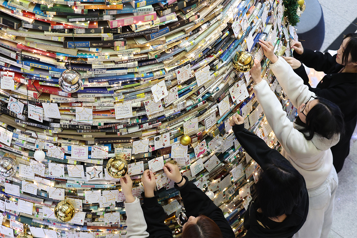 Pada tanggal 16 Desember 2025 para mahasiswa Universitas Daegu terlihat sedang memasang kertas-kertas berisi harapan mereka pada sebuah pohon Natal yang dipasang di perpustakaan Universitas Daegu kampus Gyeongsan. Pohon Natal raksasa tersebut memiliki tinggi lima meter dan lebar tiga meter yang disusun menggunakan 4.000 jilid buku. (Yonhap News)