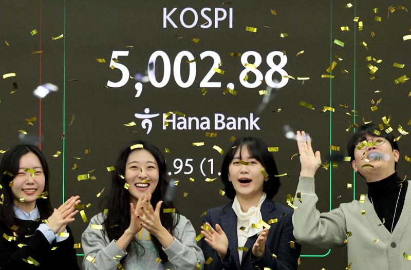 Indeks KOSPI menembus level 5.000 untuk pertama kalinya dalam sejarah. Foto di atas menunjukkan suasana para dealer yang bergembira di ruang dealing Hana Bank di Jung-gu, Seoul, pada pagi hari tanggal 22 Januari 2026. (Yonhap News)