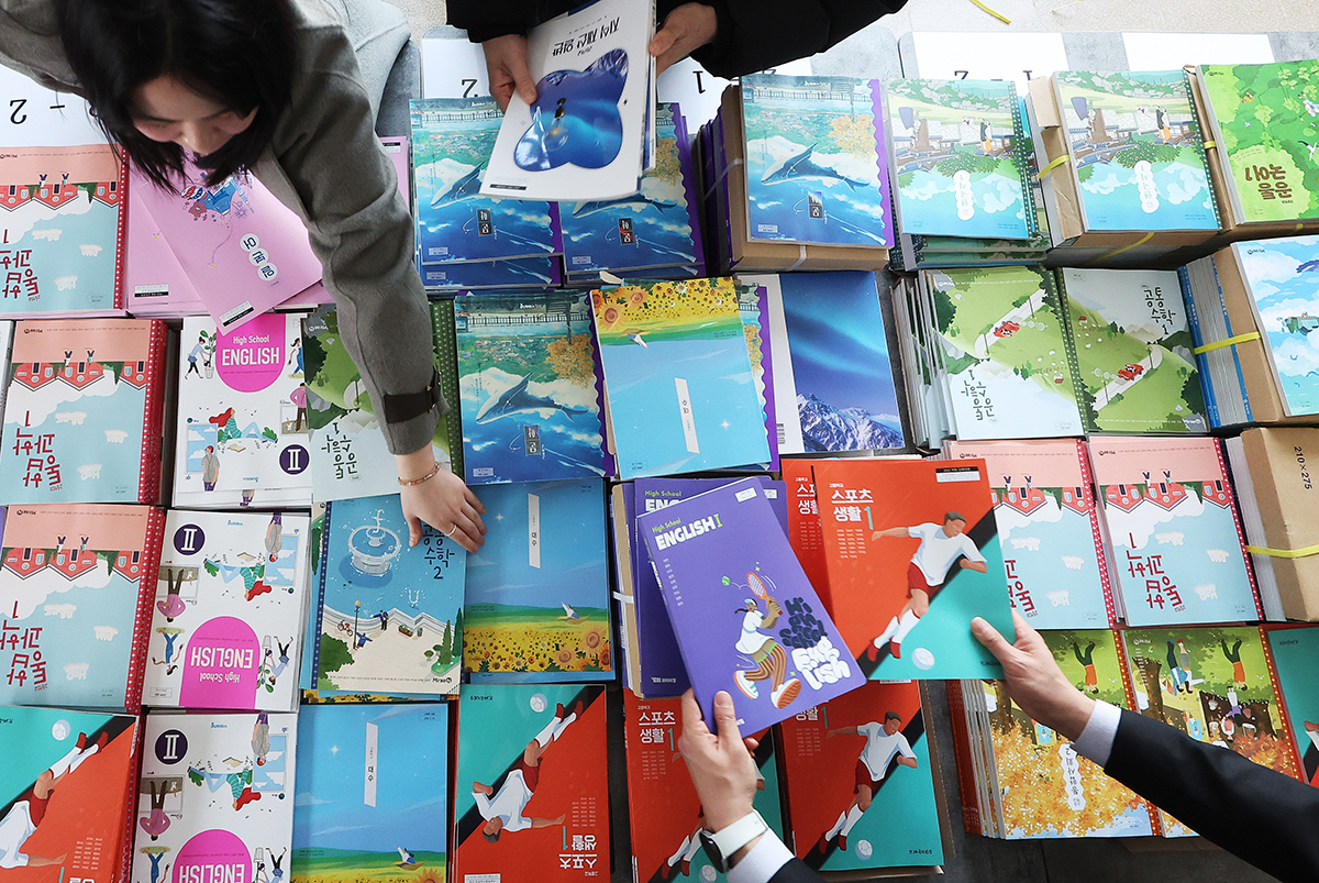 Para guru mempersiapkan berbagai buku pelajaran yang akan dibagikan kepada para murid Sekolah Menengah Kejuruan Teknik Samil pada tanggal 23 Februari 2026 di Paldal-gu, Kota Suwon, Provinsi Gyeonggi. (Yonhap News)