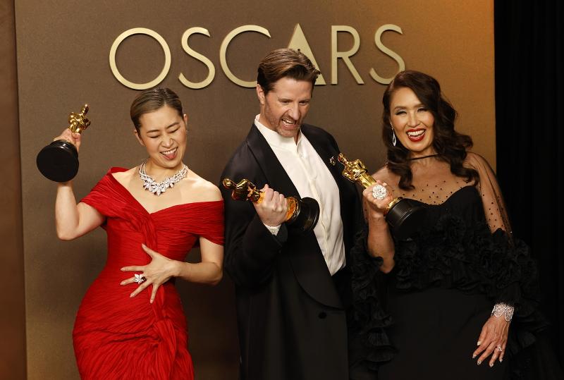 (Dari kiri ke kanan) Sutradara Maggie Kang, sutradara Chris Appelhans, dan produser Michelle Wong tersenyum sambil memegang trofi emas setelah memenangkan Film Animasi Terbaik pada Academy Awards ke-98 di Dolby Theatre, Los Angeles pada tanggal 15 Maret 2026 (waktu setempat).