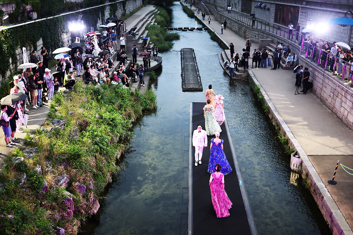 Para model terlihat sedang memperagakan busana dalam Cheonggye Live Fashion Show yang digelar di panggung air di bawah Jembatan Ogansu, Cheonggyecheon, Seoul, pada tanggal 27 Mei 2026. (Yonhap News)