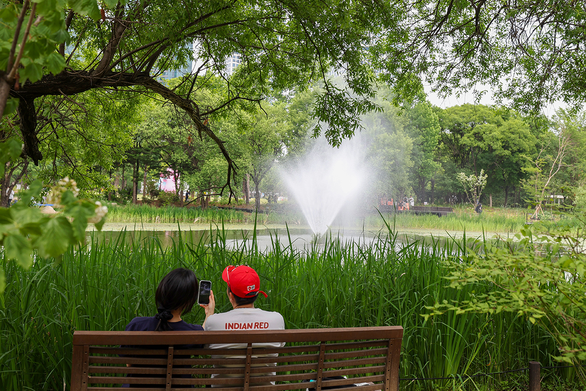 Dua warga terlihat sedang berbincang di bangku taman di tengah rindangnya pepohonan saat mengunjungi Pameran Taman Internasional Seoul 2026 di Seoul Forest, Seongdong-gu, Seoul, pada tanggal 1 Juni 2026. (Lee Jeong Woo)
