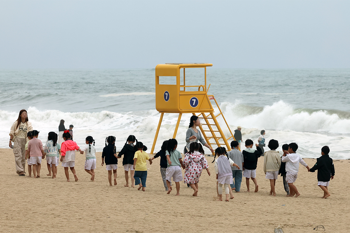Anak-anak dari sebuah tempat penitipan anak berjalan mengikuti guru mereka di pantai berpasir Pantai Gyeongpo, Gangneung, Provinsi Gangwon, pada tanggal 22 Juni 2026. (Yonhap News)