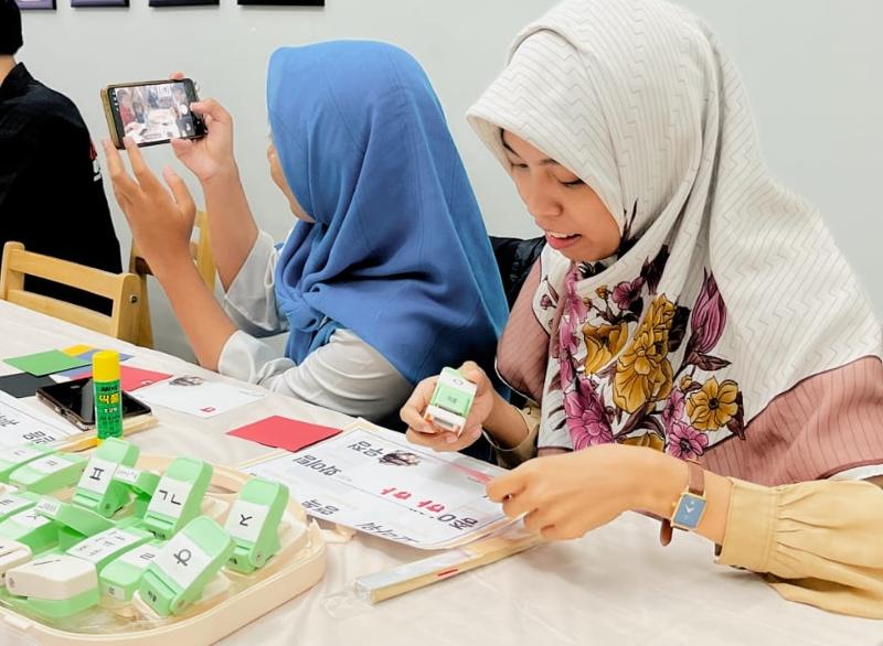 Foto penulis saat berkreasi membuat kartu ucapan bertuliskan hangeul dalam Kunjungan Kelas Budaya Korea pada tanggal 20 Mei 2026 di Akademi HKAA, Surabaya. (Humas HKAA) 