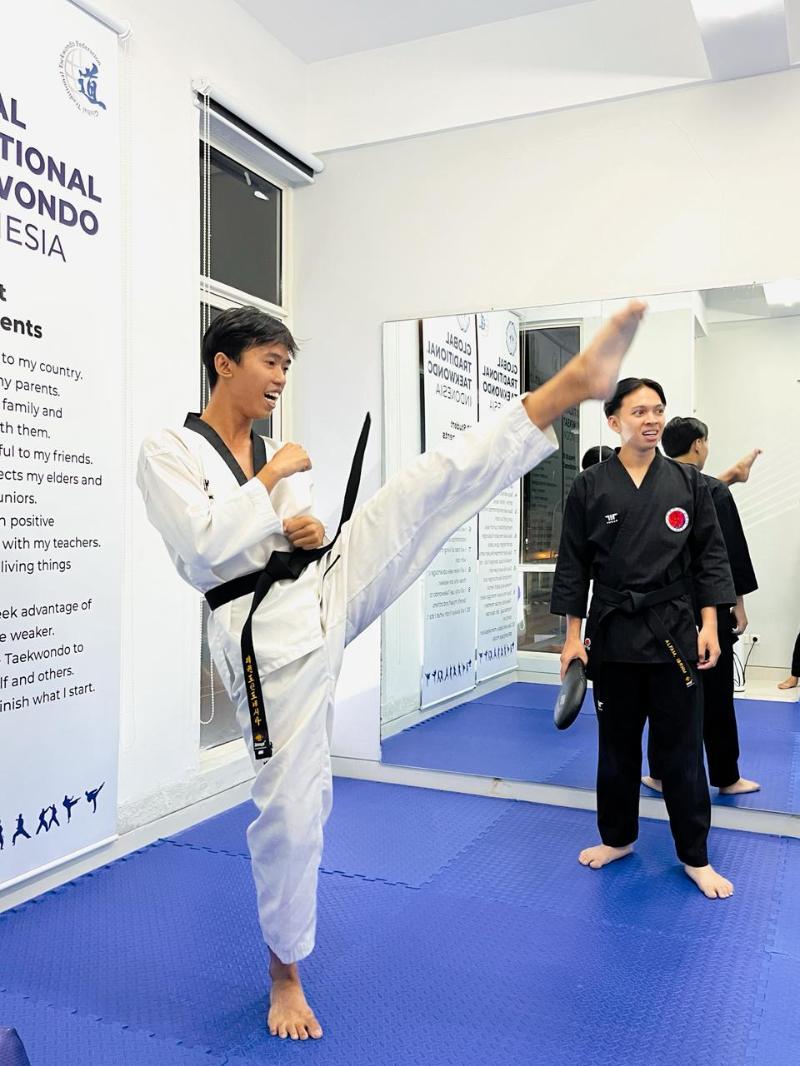 Dua orang instruktur taekwondo dari HKAA memberikan contoh gerakan tendangan dalam sesi kelas taekwondo di Kunjungan Kelas Budaya Korea yang digelar pada tanggal 20 Mei 2026 di Akademi HKAA, Surabaya. (Humas HKAA) 