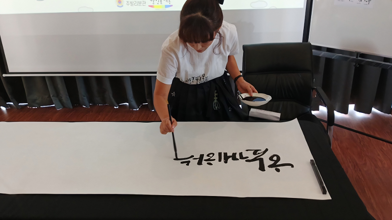Oh Soon Ok yang sedang memperagakan secara langsung cara membuat kaligrafi hangeul pada acara Sentuhan Hangeul di Ujung Jari yang digelar pada tanggal 20 Juni 2026 di Konsulat Republik Korea di Bali. 