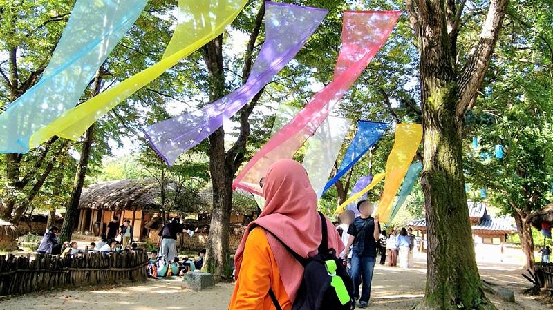 Potret penulis berfoto di jalur dengan kain sutra berwarna-warni yang digantung di pepohonan di Desa Rakyat Korea, Kota Yongin, Provinsi Gyeonggi. (Maulia Resta Mardaningtias) 