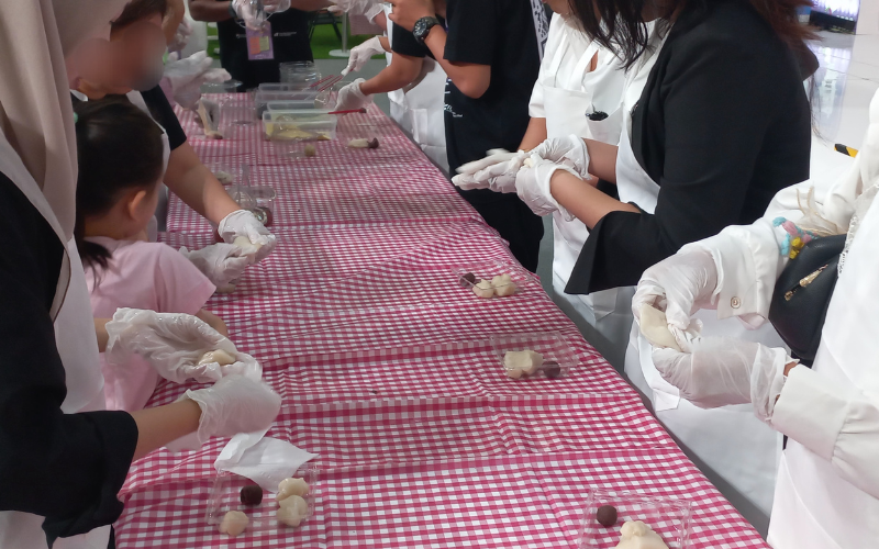 Peserta sedang membentuk adonan tok yang kemudian diisi pasta kacang merah pada sesi pertama pembuatan gyeongdan yang dilaksanakan pada tanggal 13 Juli 2026 di area Grand Atrium & Mosaic Walk, Kota Kasablanka Mall, Jakarta. 