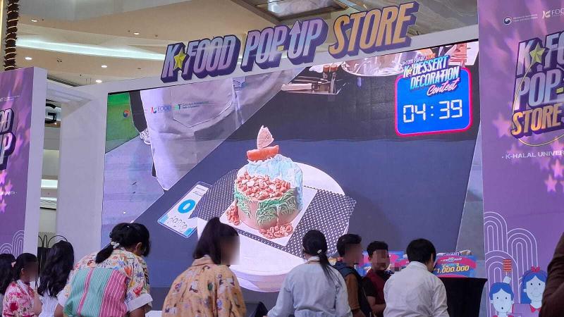 Hasil kreasi kue dari tim Qinbujang yang berjudul Pantai ditampilkan di layar utama pada K-Dessert Decoration Contest tanggal 19 Juli 2026 di Mal Kota Kasablanka, Jakarta. 