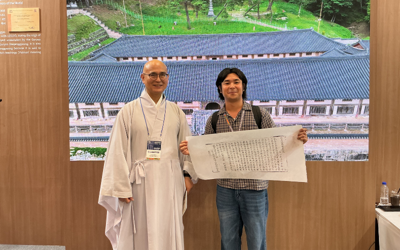 Penulis berfoto bersama seorang biksu yang menjaga stan Kuil Haeinsa di K-Heritage House pada tanggal 22 Juli 2026 di BEXCO, Haeundae-gu, Busan. 