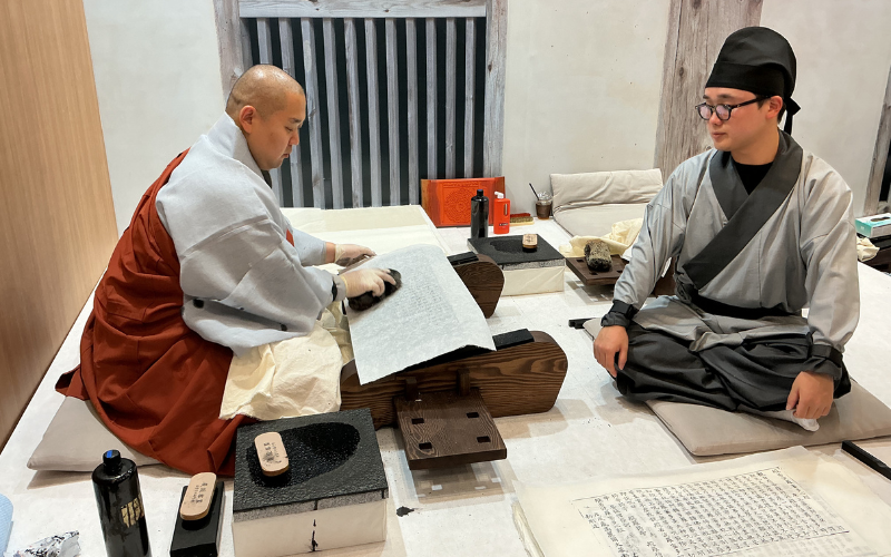 Prosesi pembuatan hasil cetakan Tripitaka Koreana menggunakan cat pada kertas di stan Kuil Haeinsa di K-Heritage House pada tanggal 22 Juli 2026 di BEXCO, Haeundae-gu, Busan.  