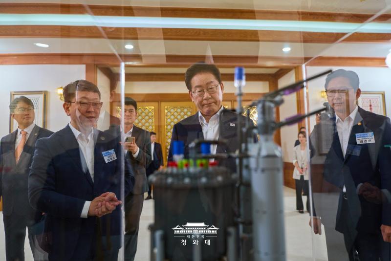 Presiden Lee Jae Myung (tengah) melihat model kapal kontainer yang dilengkapi SMR sebelum menghadiri Pertemuan Pemaparan Tujuh SEED Penggerak Pertumbuhan Masa Depan pada tanggal 12 Agustus 2026 di Cheong Wa Dae.  
