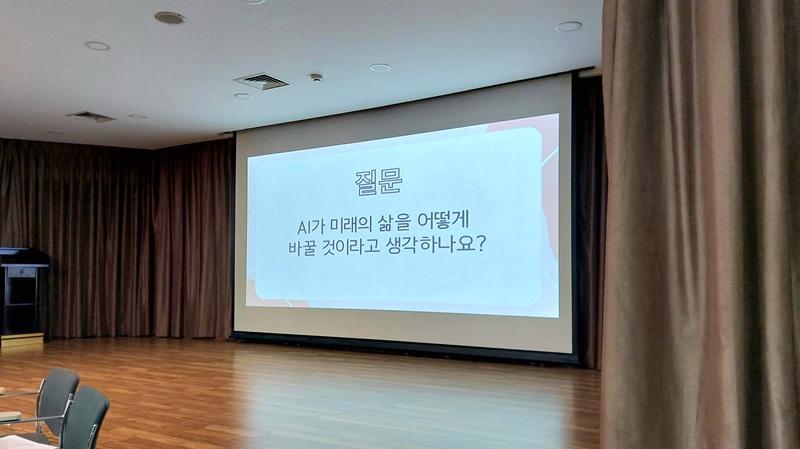 Layar proyektor menampilkan pertanyaan Bagaimana kecerdasan buatan (AI) akan mengubah kehidupan di masa depan? dalam acara Ruang Bicara Bahasa Korea yang berlangsung pada hari Senin (10/08/2026) di KCCI, Jakarta. 