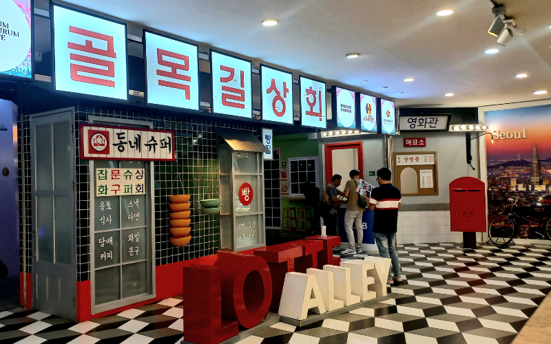 Area depan dengan ornamen bertulisan hangeul sebagai pintu masuk ke instalasi nuansa Korea yang dipotret pada tanggal 15 Agustus 2026 di Lotte Alley, Jakarta. 