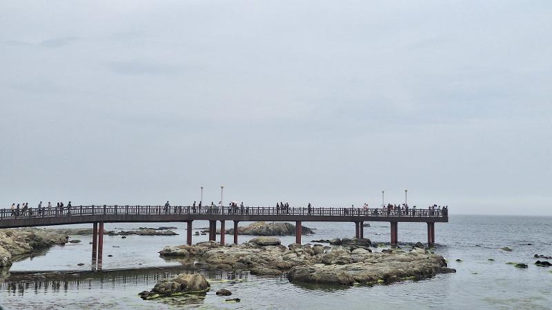 Pemandangan sekelompok wisatawan yang berjalan di teras pantai untuk berfoto dan menikmati pemandangan di Alun-alun Matahari Terbit Homigot yang terletak di Nam-gu, Kota Pohang, Provinsi Gyeongsangbuk. Foto tersebut diambil pada tanggal 18 Juli 2026. 
