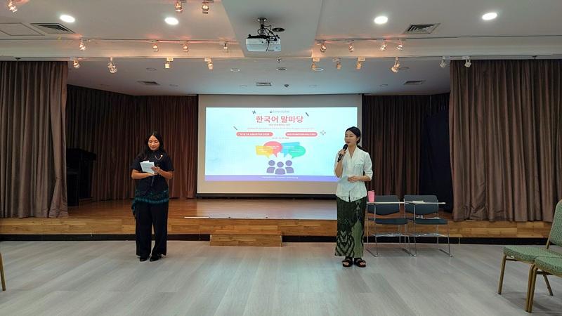 Potret dua staf KCCI yang bertugas sebagai fasilitator acara, mengenakan pakaian tradisional Indonesia berupa batik dan kebaya, menyesuaikan tema Perbedaan Budaya dalam Ruang Bicara Bahasa Korea pada Senin (24/08/2026). (Maulia Resta Mardaningtias) 