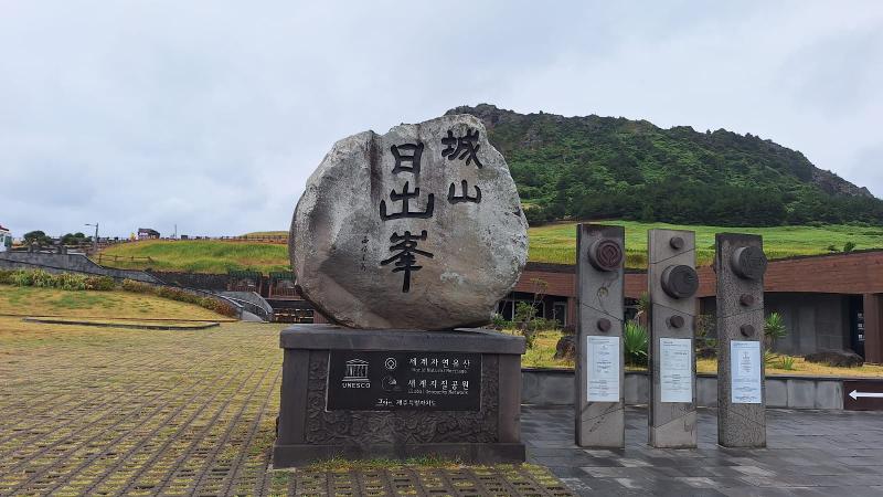 Batu penanda yang terdapat di dekat pintu masuk Seongsan Ilchulbong menunjukkan bahwa Seongsan Ilchulbong terdaftar sebagai salah satu Situs Warisan Alam Dunia UNESCO. Foto tersebut diambil pada tanggal 15 Agustus 2026. 