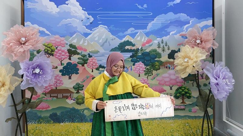 Potret penulis mengabadikan momen mengenakan hanbok dan tulisan petikan puisi penyair Do Jong-hwan berjudul “Bunga yang Mekar Kala Terguncang” di latar khusus yang disediakan oleh Korean Cultural Center Indonesia (KCCI) pada tanggal 29 Agustus 2026 di ANTARA Heritage Center, Jakarta. (Maulia Resta Mardaningtias)  