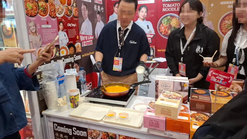 Potret seorang staf di stan produk makanan melakukan demo memasak tokpoki pada JIPREMIUM 2026 hari pertama tanggal 3 September 2026 di JICC, Jakarta.  
