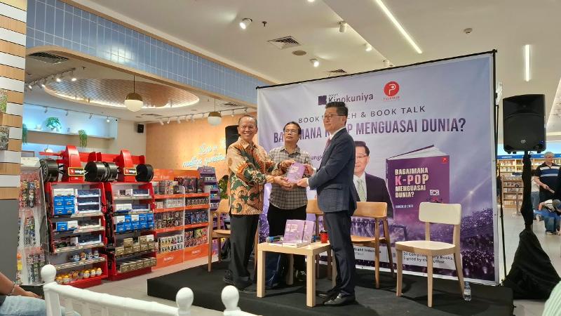 Tri Haryono selaku perwakilan Penerbit Palmerah Syndicate, Zaini selaku dosen BKK UI, dan Choi Jungkiu selaku penulis buku berfoto bersama pada peluncuran buku Bagaimana K-Pop Menguasai Dunia? sebelum bincang buku berlangsung tanggal 27 September 2026 di Toko Buku Kinokuniya Grand Indonesia, Jakarta. 