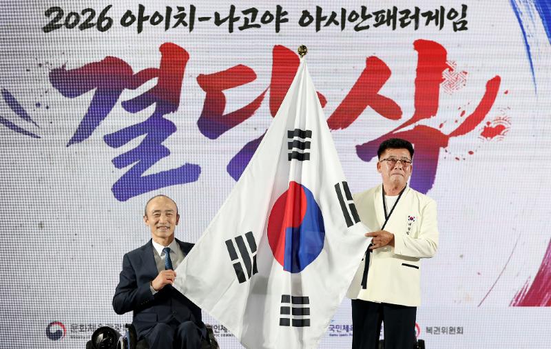 Ketua Kontingen Korea, Park Heung Sik, (kanan) bersama Ketua Komite Paralimpiade Korea, Jeong Jin Wan, memegang bendera kontingen dalam upacara pelepasan kontingen untuk Asian Para Games Aichi-Nagoya 2026 pada tanggal 6 Oktober 2026 di Pusat Pelatihan Atlet Icheon milik Komite Paralimpiade Korea, Kota Icheon, Provinsi Gyeonggi.