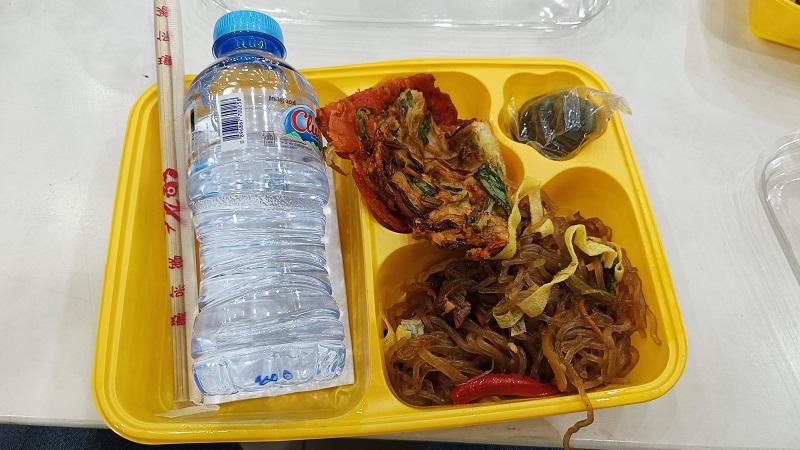 Menu makan sore berupa jabce, pajeon (panekuk daun bawang), songpyeon*(kue beras berbentuk setengah bulan), dan air mineral pada tanggal 19 September 2026 di lantai 7 Graha Widya Mandala, Surabaya. 