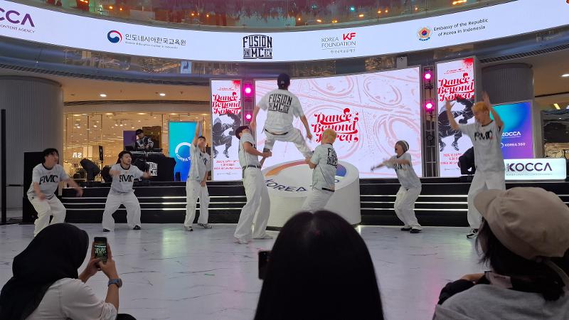 Potret tiga anggota Fusion MC menampilkan aksi akrobatik sambil disemangati oleh anggota lainnya pada pertunjukan Dance Beyond Korea tanggal 19 Oktober 2026 di Main Atrium KOREA 360, Jakarta. 